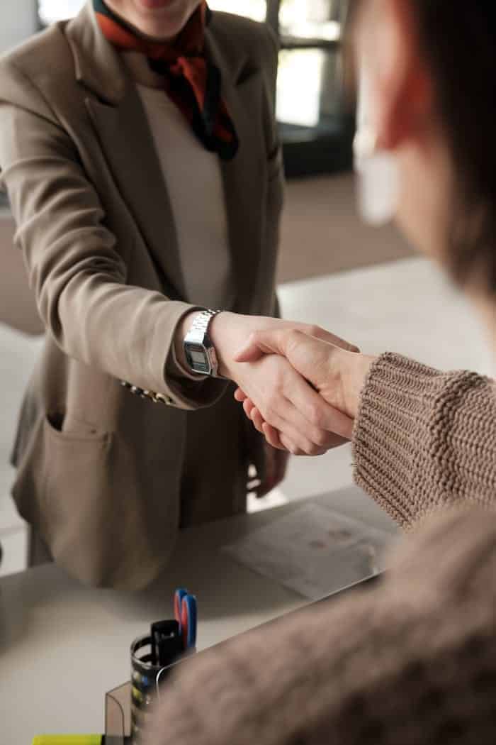 our-story-01 Two professionals shaking hands in an office, signifying a successful business agreement.